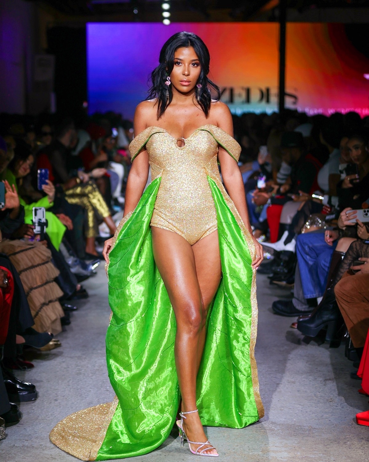 Gold bodysuit with kelly green cape on runway